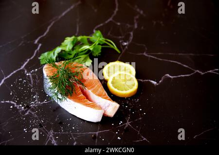 Filet de saumon avec citron, persil et aneth sur fond noir Banque D'Images