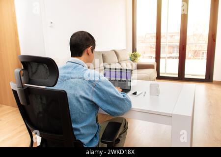 Vue arrière d'un homme d'affaires méconnu travaillant sur son ordinateur portable au bureau à la maison Banque D'Images