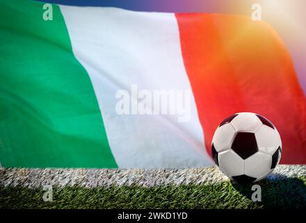 Football ou football sur herbe verte, sur fond de drapeau italien Banque D'Images