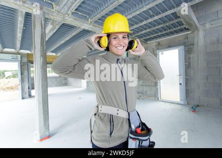 femme bâtisseuse mettant ses cache-oreilles Banque D'Images