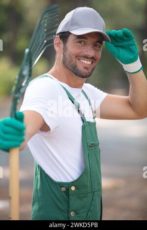 homme travaillant dans le jardin de campagne tenant le râteau de congé Banque D'Images