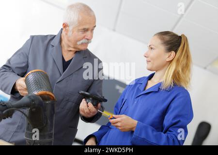 mécanicien féminin avec mentor travaillant sur le filtre à air du véhicule Banque D'Images