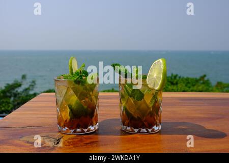 Cocktails long Island Ice Tea, avec un fond de mer bleu. Banque D'Images