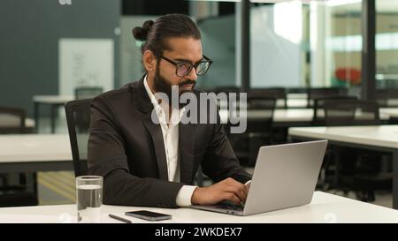 Occupé concentré indien employeur masculin entreprise entrepreneur arabe patron PDG homme d'affaires musulman homme d'affaires au bureau avec ordinateur portable de travail Banque D'Images