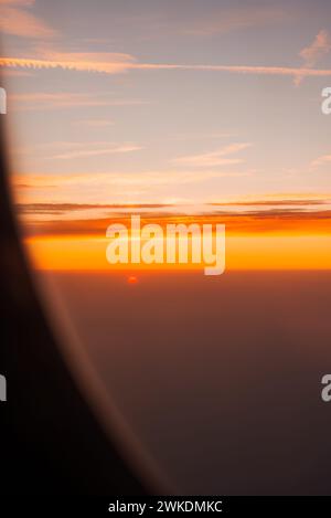 Profitez de la vue sur le coucher du soleil depuis une fenêtre d'avion tout en planant à haute altitude Banque D'Images