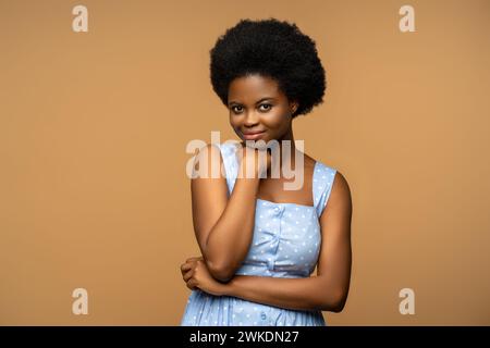 Heureux afro-américain belle femme regarder dans la caméra avec le sourire timide, tourné sur fond de studio Banque D'Images
