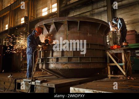 2015-05-25 - Marioupol, Ukraine. Chantier naval d'Azov. Les ouvriers industriels soudent une grande poche métallurgique pour l'acier. Les hommes en équipement de protection performent Banque D'Images