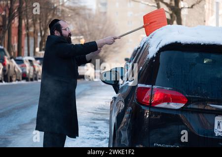 Par un froid matin d'hiver, un homme juif orthodoxe nettoie la neige de son SUV Banque D'Images