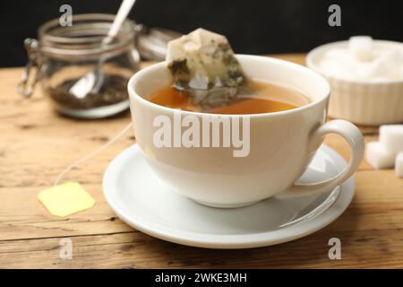 Infusion de thé. Tasse blanche avec sachet de thé sur table en bois, gros plan Banque D'Images