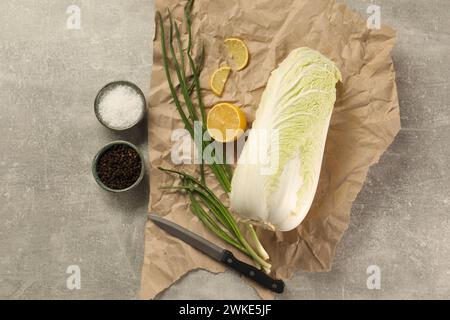 Chou chinois frais, citron, oignon vert et épices sur table gris clair, pose à plat Banque D'Images