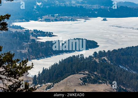 Perspective élevée du réservoir d'eau Dospat et de la ville dans le sud de la Bulgarie, eau gelée, neige couverte de montagnes Rhodope en hiver Banque D'Images