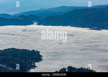 Perspective élevée du réservoir d'eau Dospat et de la ville dans le sud de la Bulgarie, eau gelée, neige couverte de montagnes Rhodope en hiver Banque D'Images