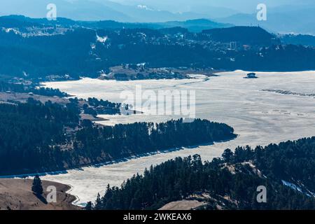 Perspective élevée du réservoir d'eau Dospat et de la ville dans le sud de la Bulgarie, eau gelée, neige couverte de montagnes Rhodope en hiver Banque D'Images