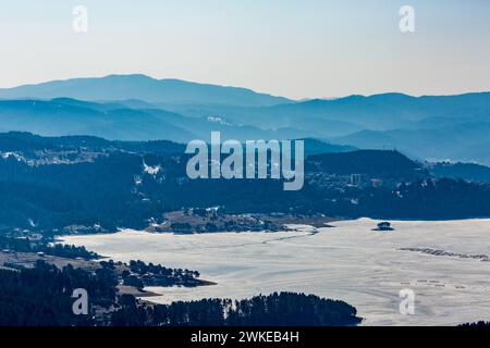 Perspective élevée du réservoir d'eau Dospat et de la ville dans le sud de la Bulgarie, eau gelée, neige couverte de montagnes Rhodope en hiver Banque D'Images