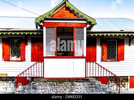 Une maison en bois avec cadres rouges et toit vert en Dominique Banque D'Images