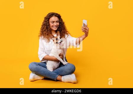 Femme aux cheveux bouclés prend selfie avec son joyeux Jack Russell Banque D'Images