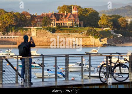 Touriste avec un vélo sur la jetée du Club nautique, Puerto de Donostia, Bahia de la Concha, Miramar Palace, Donostia, San Sebastian, Basque Coun Banque D'Images