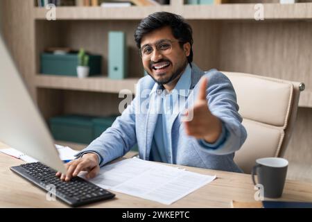 Homme d'affaires indien joyeux tenant la main dans la salutation offrant une poignée de main à l'intérieur Banque D'Images