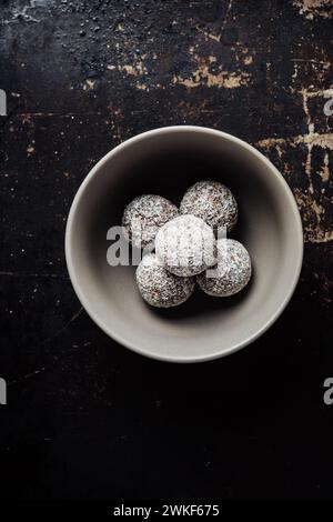 Bonbons faits maison en flocons de noix de coco sur un fond sombre. Banque D'Images