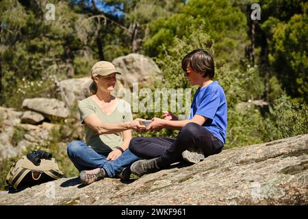 Mère et fils assis sur un rocher avec une boîte à lunch en acier inoxydable dans la forêt. Banque D'Images