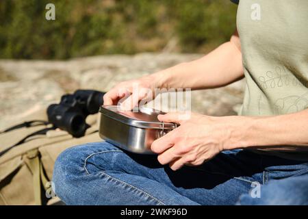 Femme assise avec une boîte à lunch en acier inoxydable dans la forêt. Banque D'Images