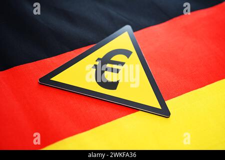 FOTOMONTAGE, Warnschild mit Eurozeichen auf einer Deutschlandfahne, Symbolfoto für Haushaltskrise und Rezession *** PHOTOMONTAGE, panneau d'avertissement avec le symbole de l'euro sur un drapeau allemand, photo symbolique pour la crise budgétaire et la récession Banque D'Images