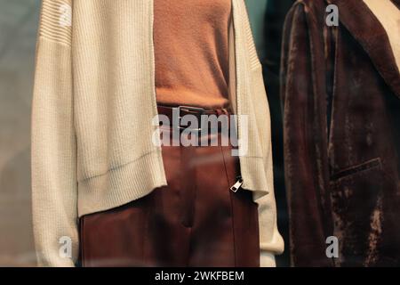 Détails d'un pull tricoté blanc et d'un pantalon marron avec une ceinture en cuir. Vêtements et accessoires de mode décontractés pour femmes Banque D'Images