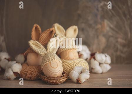 Oeufs de Pâques dans des chapeaux tricotés au crochet avec des oreilles de lapin dans le nid. Concept de célébration de Pâques Banque D'Images