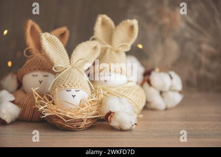 Oeufs de Pâques dans des chapeaux tricotés au crochet avec des oreilles de lapin dans le nid. Concept de célébration de Pâques Banque D'Images