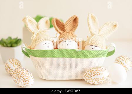 Oeufs de Pâques dans des chapeaux tricotés au crochet avec des oreilles de lapin dans le nid. Concept de célébration de Pâques Banque D'Images