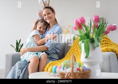 Jeune mère et sa petite fille portant des oreilles de lapin à la maison. Fête de Pâques Banque D'Images
