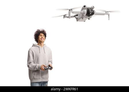 Heureux jeune homme volant un drone avec un dispositif de cotroller et regardant isolé sur fond blanc Banque D'Images