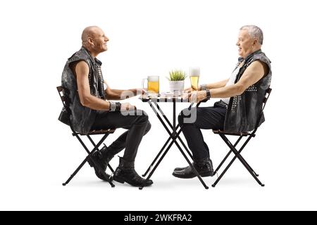 Hommes en gilets de cuir assis à une table et ayant de la bière isolé sur fond blanc Banque D'Images