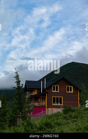 Une grande maison en bois pour les touristes dans les montagnes, une jeune fille se dresse sur la terrasse sur fond des Carpates, une maison pour Banque D'Images