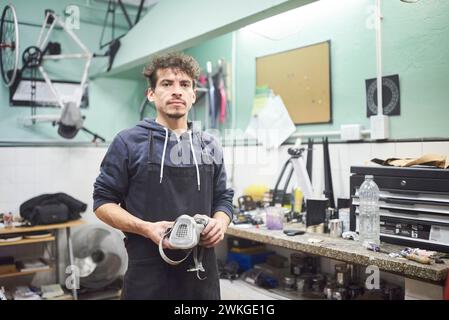 Portrait d'un jeune travailleur latin debout dans son atelier portant un masque de protection respiratoire. De vraies personnes au travail. Banque D'Images