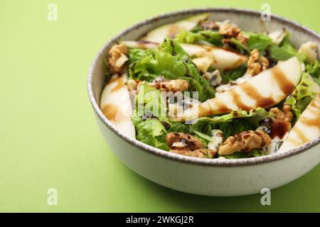 Délicieuse salade de poires avec sauce dans un bol sur fond vert, gros plan Banque D'Images