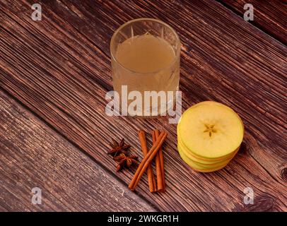 Liqueur de pomme aux épices, alcool maison dans un bol en cristal avec cannelle et anis sur une table en bois. Vue de dessus, pose à plat. Banque D'Images