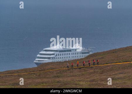 Les passagers du navire de croisière Stella Australis en gilets de sauvetage marchent sous la tempête et la pluie jusqu'au cap Horn, point le plus méridional de l'Amérique, Horn Island, Cabo Banque D'Images