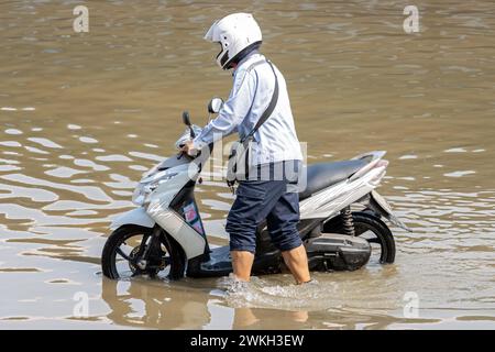 Un homme pousse une moto dans une rue inondée, Thaïlande Banque D'Images
