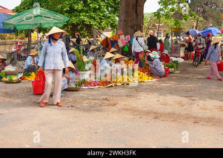 Ville de Hue, Vietnam 21 mars 2015 : femmes ornées de chapeaux traditionnels vendant des fleurs colorées au marché de rue extérieur animé à l'ombre de parapluies, wi Banque D'Images