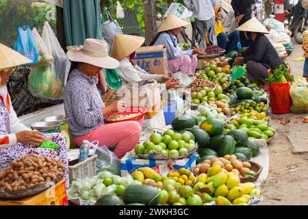 Ville de Hue, Vietnam 21 mars 2015 : les femmes ornées de chapeaux traditionnels vendent des fruits colorés dans un marché de rue traditionnel animé Banque D'Images