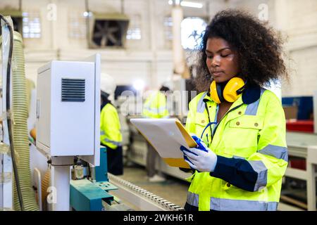 Les femmes noires africaines travaillent avec l'industrie de l'usine de meubles de machine de coupe de bois avec combinaison de sécurité Banque D'Images