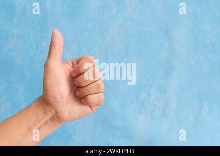 Jeune homme main asiatique faisant des pouces vers le haut signe isolé sur fond bleu. Banque D'Images