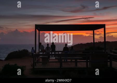Groupe d'amis profiter du coucher de soleil tranquille au bord de l'océan Atlantique depuis un point de vue sur la côte de l'Algarve à Lagos, Portugal. Banque D'Images