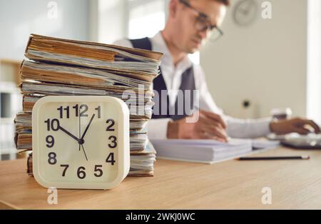 Horloge de table et pile de papiers sur le bureau Banque D'Images