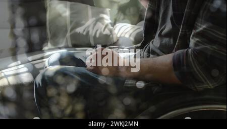 Image de taches lumineuses sur un homme caucasien handicapé assis en fauteuil roulant Banque D'Images