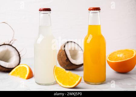 Savoureux kombucha dans des bouteilles en verre et des fruits frais sur une table blanche Banque D'Images