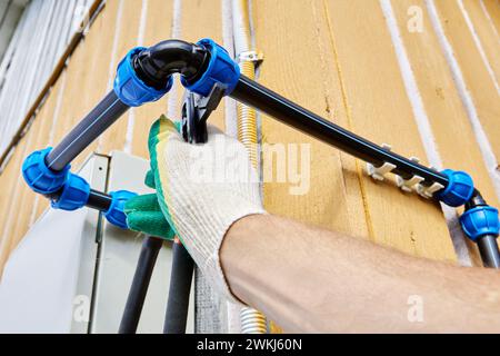 Les raccords de compression coudés pour tuyaux HDPE sont utilisés lors de l'installation de tuyaux d'eau potable et d'irrigation externes pour l'eau froide, le plombier se resserre Banque D'Images