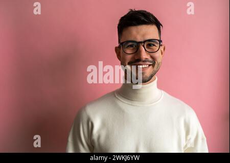 Homme en lunettes, pull blanc à col roulé avec sourire et barbe Banque D'Images