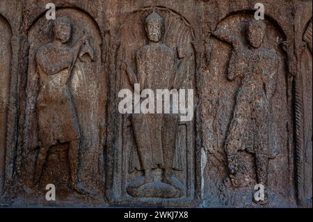 Trois personnages masculins, sculptés en relief à l'entrée de la basilique du monastère de Santa Maria de Ripoll dans la province de Gérone, Catalogne, Espagne. L'entrée a été sculptée au milieu des années 1100 dans un style roman lombard. Les trois figures de cette image tiennent chacune des objets, la figure centrale tenant un bâton ou une tige d'autorité dans sa main droite et un livre dans sa gauche. Banque D'Images